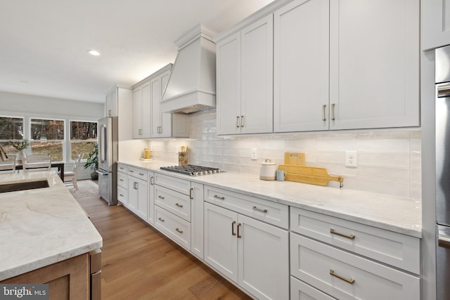 kitchen featuring a sink, stainless steel appliances, premium range hood, tasteful backsplash, and recessed lighting