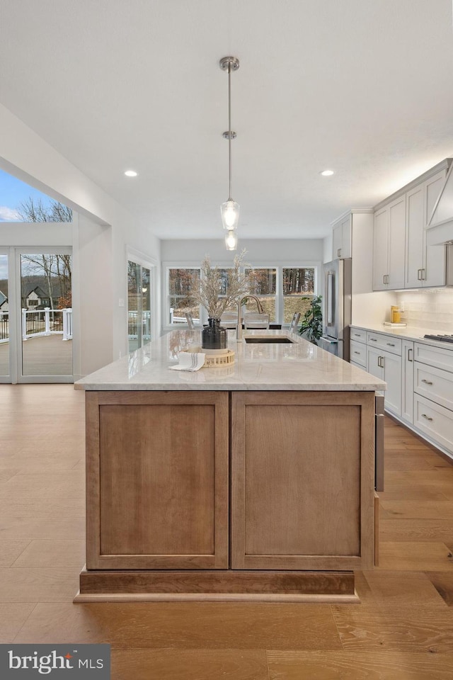 kitchen with a sink, stainless steel appliances, a large island, light stone counters, and recessed lighting