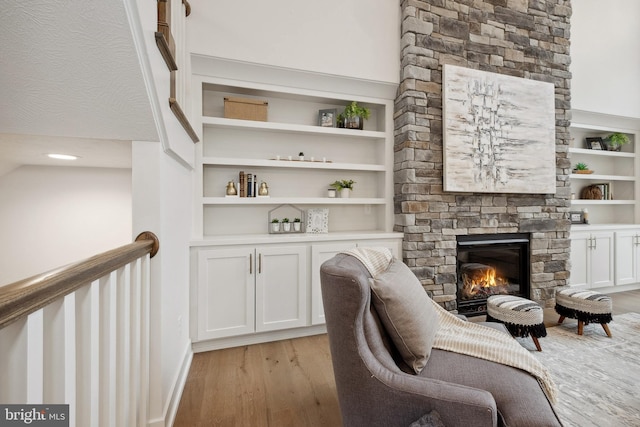 sitting room featuring baseboards, light wood finished floors, a fireplace, and built in features