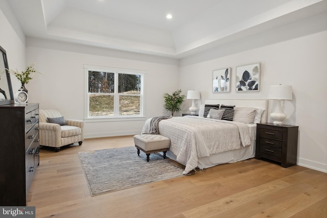 bedroom featuring a raised ceiling, baseboards, light wood-type flooring, and recessed lighting
