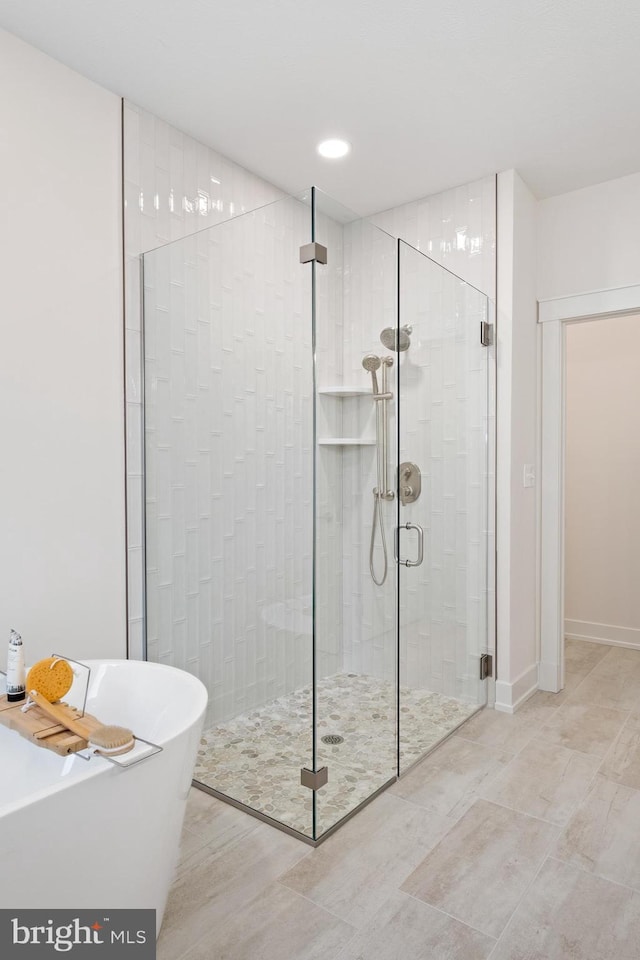bathroom featuring recessed lighting, a stall shower, and a freestanding tub