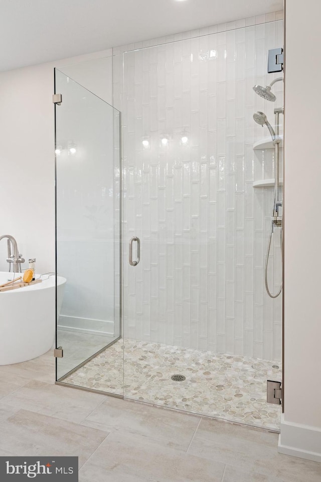 bathroom with a stall shower, tile patterned floors, and a freestanding bath