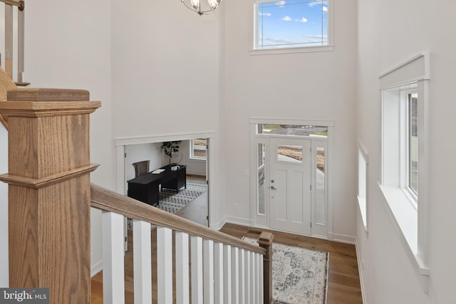 entryway featuring a high ceiling, a notable chandelier, baseboards, and wood finished floors