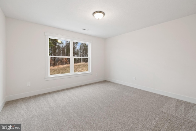 carpeted spare room with visible vents and baseboards