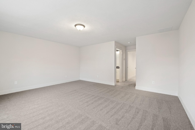 empty room featuring carpet and baseboards