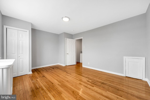 unfurnished bedroom featuring baseboards, a closet, and light wood-style floors