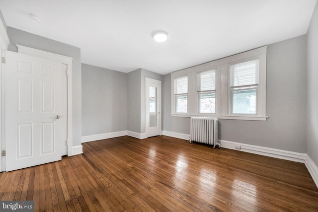 spare room with wood-type flooring, baseboards, and radiator
