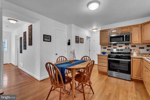 kitchen with light wood finished floors, light countertops, baseboards, and stainless steel appliances