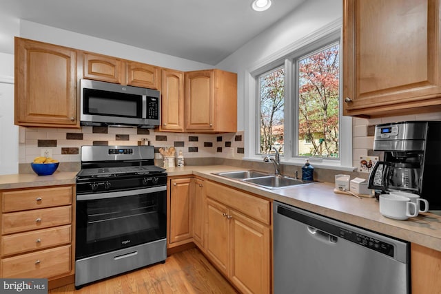 kitchen with a sink, light countertops, tasteful backsplash, and stainless steel appliances