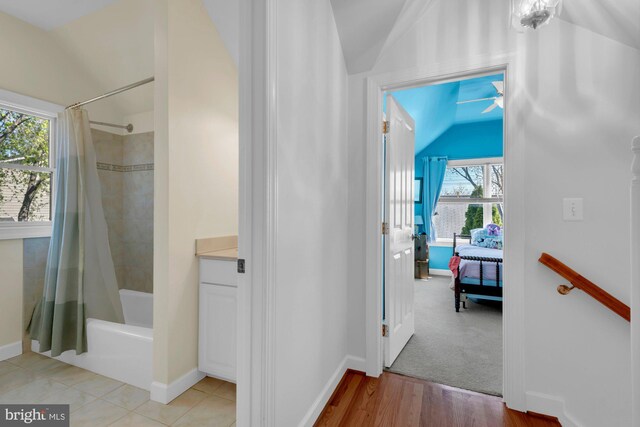 hallway featuring light wood-type flooring, baseboards, and lofted ceiling