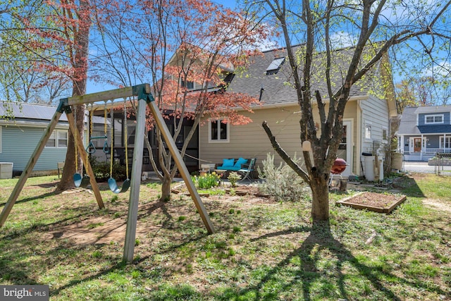 back of house with a playground and roof with shingles