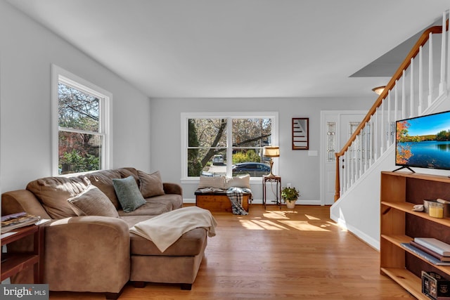 living area featuring stairs, baseboards, and wood finished floors