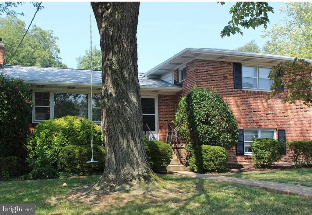 split level home featuring a front lawn and brick siding