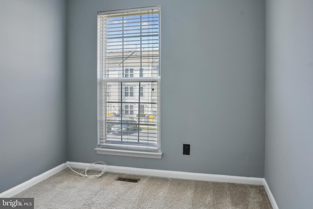carpeted spare room with visible vents and baseboards