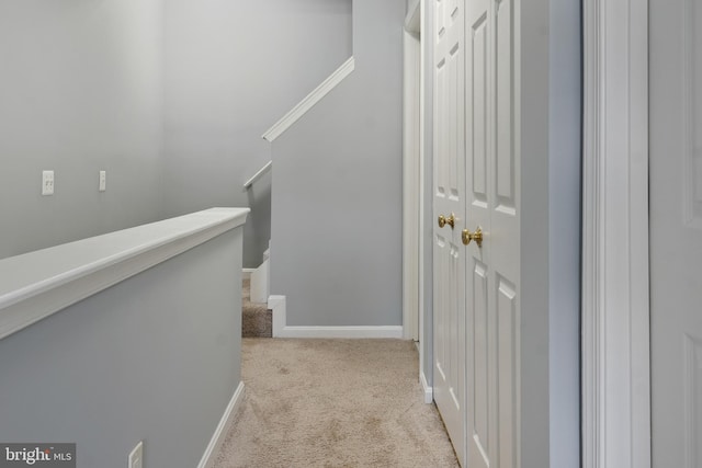 hallway featuring baseboards, carpet flooring, and an upstairs landing