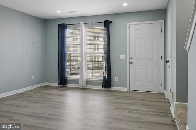 unfurnished room featuring wood finished floors, a wealth of natural light, and baseboards