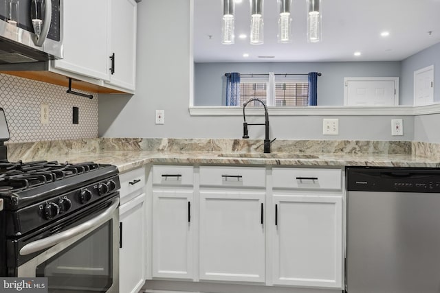kitchen featuring white cabinets, a sink, recessed lighting, decorative backsplash, and appliances with stainless steel finishes