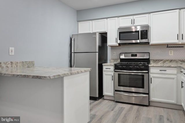 kitchen featuring tasteful backsplash, white cabinetry, light wood finished floors, and stainless steel appliances