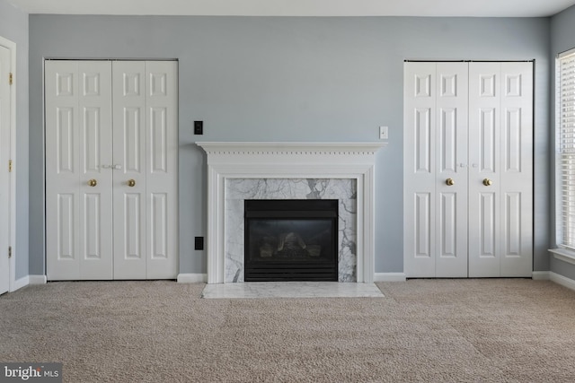 unfurnished living room with baseboards, carpet floors, and a high end fireplace