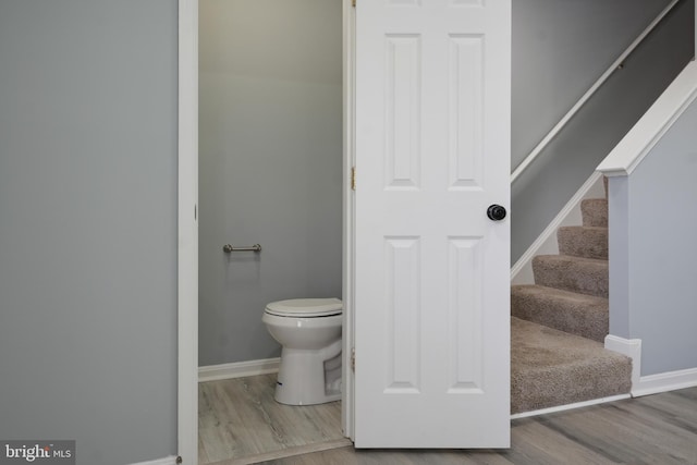 bathroom with baseboards, wood finished floors, and toilet