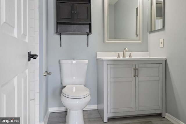 bathroom with baseboards, toilet, vanity, and wood finished floors