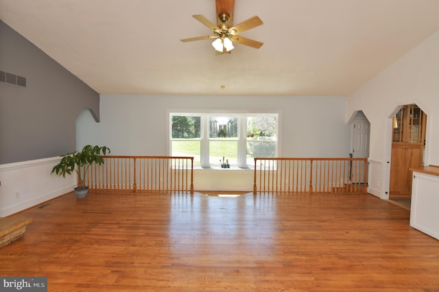 additional living space featuring arched walkways, vaulted ceiling, light wood finished floors, visible vents, and a ceiling fan