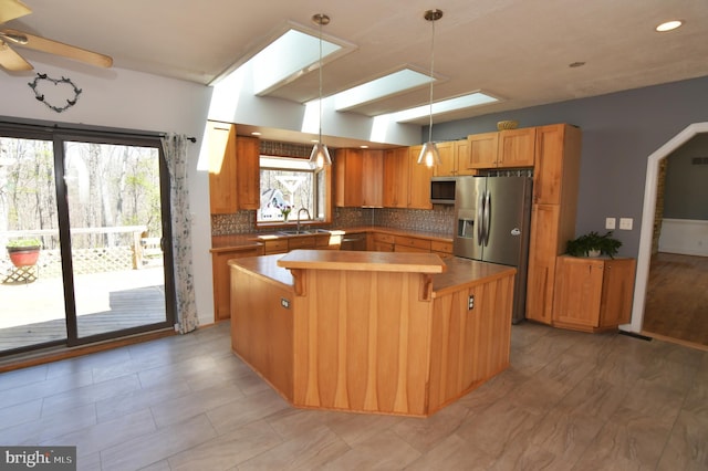 kitchen with tasteful backsplash, stainless steel appliances, decorative light fixtures, and a kitchen island