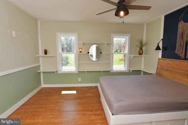bedroom featuring baseboards, wood finished floors, and ceiling fan
