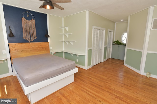 bedroom featuring baseboards, visible vents, wood finished floors, and multiple closets