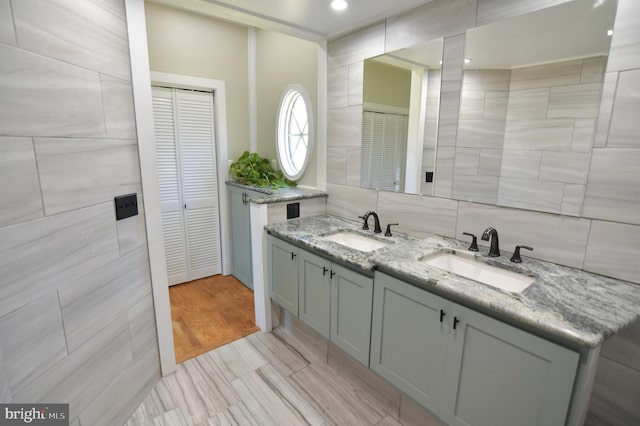 full bathroom featuring tasteful backsplash, double vanity, a closet, and a sink