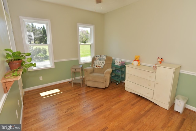 sitting room with a healthy amount of sunlight, light wood finished floors, and baseboards