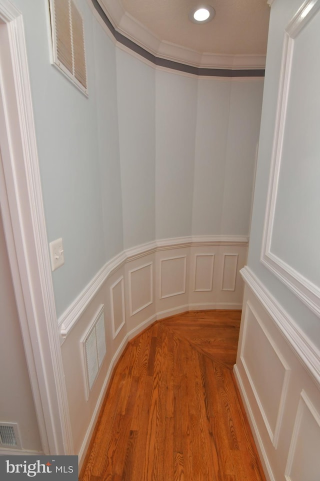 details featuring crown molding, visible vents, and wood finished floors