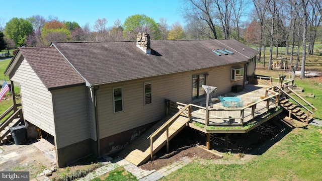 back of house with stairs, a chimney, a wooden deck, and roof with shingles