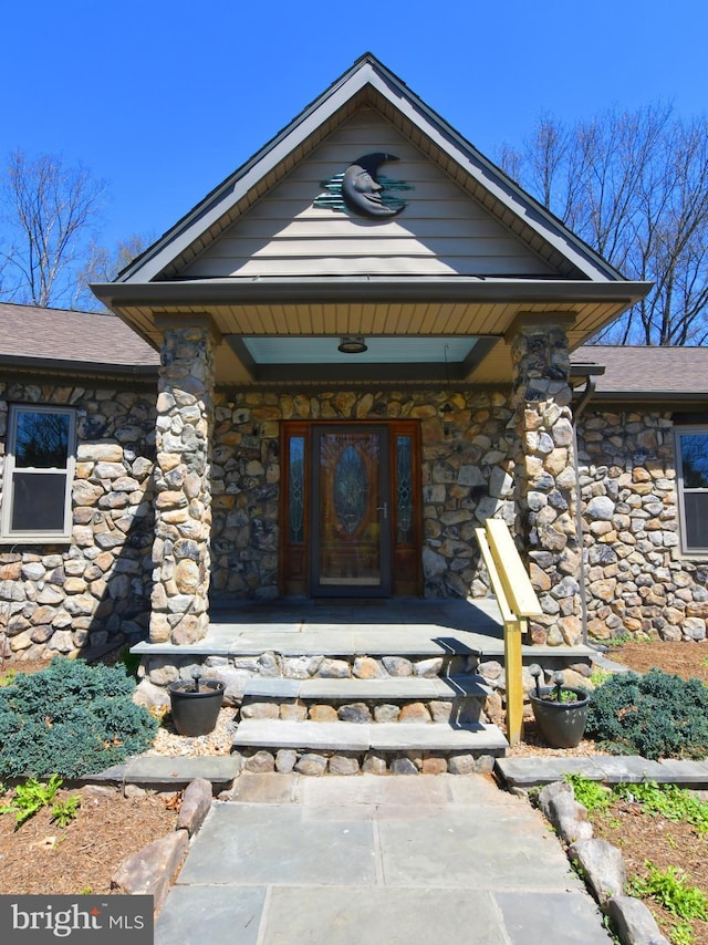 view of exterior entry with covered porch and stone siding