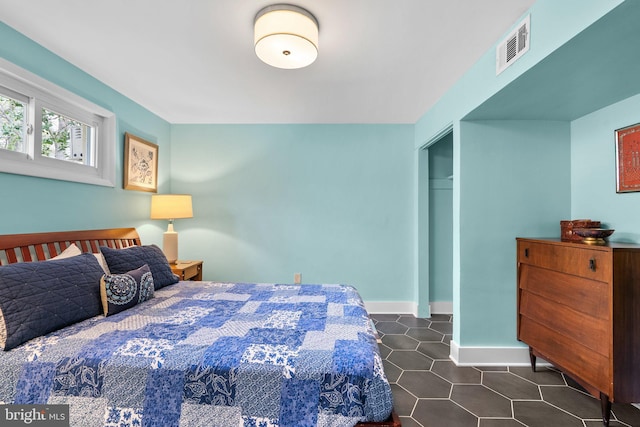 bedroom featuring baseboards, dark tile patterned floors, and visible vents