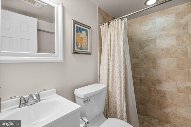 bathroom featuring tiled shower, vanity, visible vents, and toilet