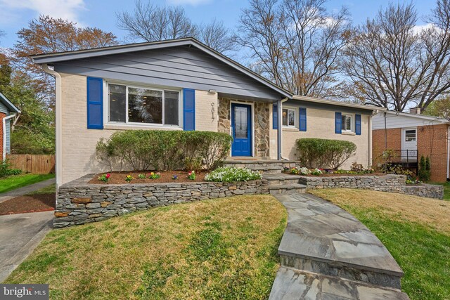 view of front of home featuring brick siding, a front lawn, and fence