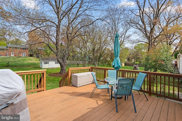 deck featuring an outdoor structure, outdoor dining area, a storage shed, a yard, and fence