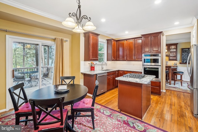 kitchen featuring crown molding, light wood-style flooring, a kitchen island, a sink, and stainless steel appliances