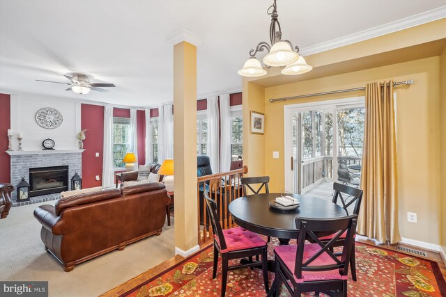 dining space featuring a fireplace, baseboards, crown molding, and ceiling fan