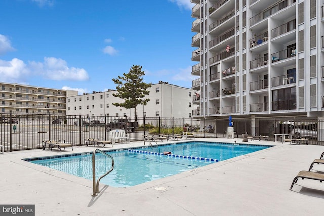 community pool with a patio area and fence