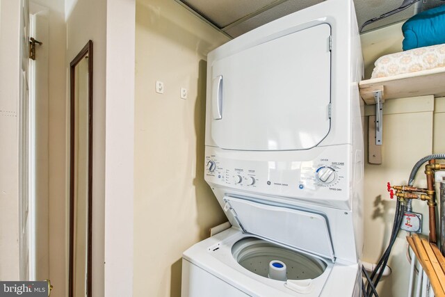 clothes washing area featuring stacked washer and dryer and laundry area
