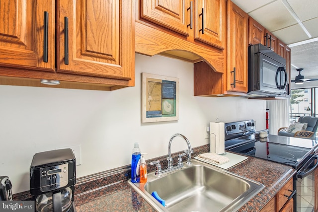 kitchen featuring black microwave, dark countertops, brown cabinetry, stainless steel electric stove, and a sink