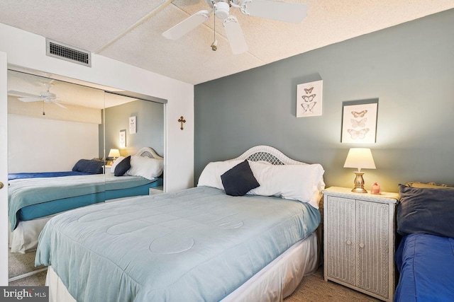bedroom featuring visible vents, a closet, ceiling fan, carpet, and a textured ceiling
