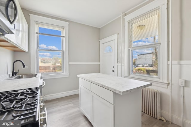 4011 Hayward Ave, Baltimore, MD 21215 - kitchen featuring baseboards, white cabinetry, radiator heating unit, light wood-style floors, and a sink