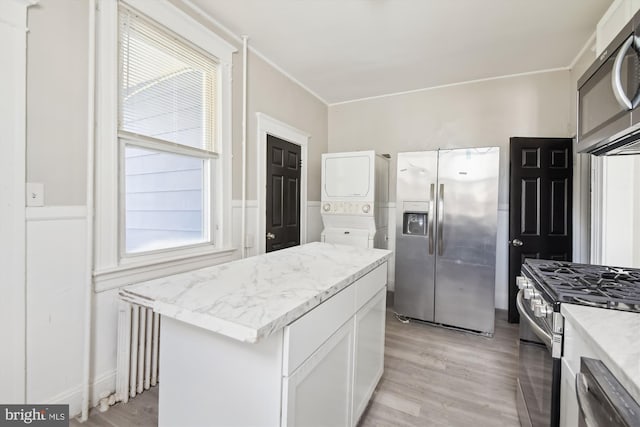 4011 Hayward Ave, Baltimore, MD 21215 - kitchen with light stone countertops, appliances with stainless steel finishes, stacked washing maching and dryer, and light wood finished floors