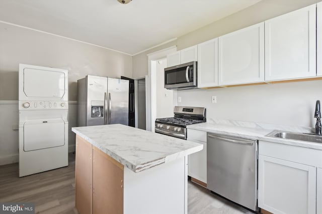 4011 Hayward Ave, Baltimore, MD 21215 - kitchen featuring light wood-type flooring, stacked washer and dryer, a sink, and stainless steel appliances