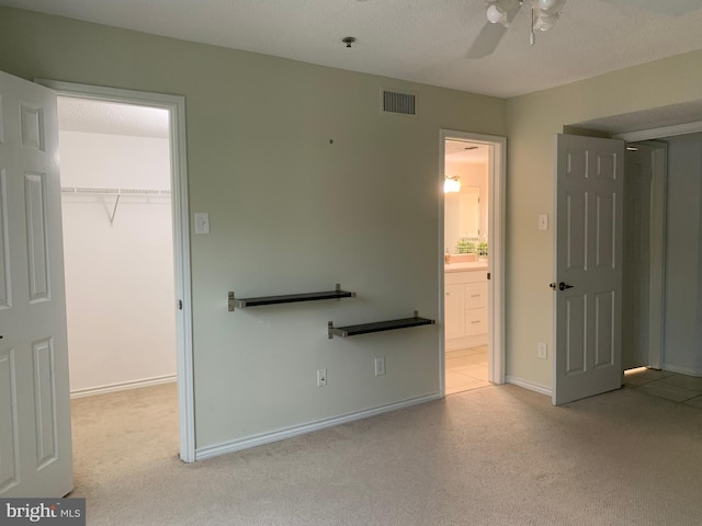 unfurnished bedroom with a spacious closet, carpet, a closet, and ensuite bath