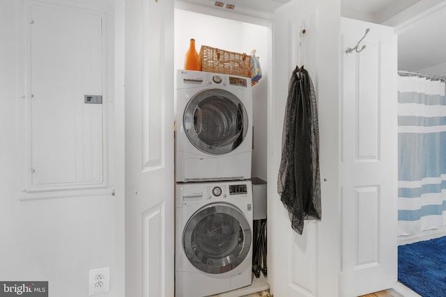 washroom with laundry area, electric panel, and stacked washer / drying machine