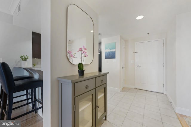hallway with recessed lighting, light tile patterned floors, visible vents, and baseboards